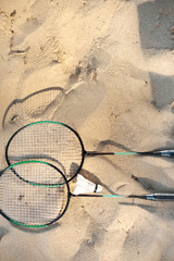 Fototapeta na wymiar close up view of badminton racquets and shuttlecock lying on sandy beach