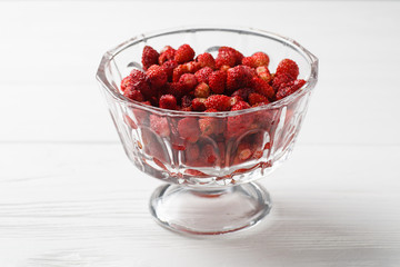 Fresh strawberry fruit in a glass dish on a white background.