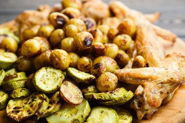 Grilled vegetables and chicken wings on the wooden plate