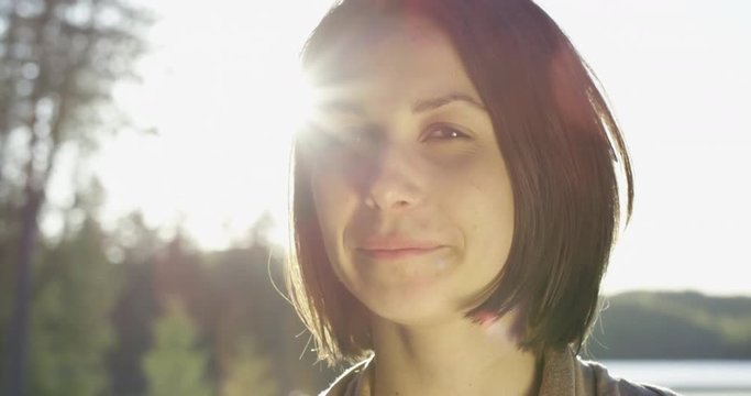 Beautiful woman smiling towards camera with big sunflare behind her - summer fun