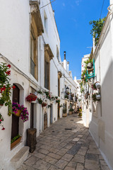 A street in Locorotondo with typical whitewashed houses and hanging flowers, Apulia, Italy