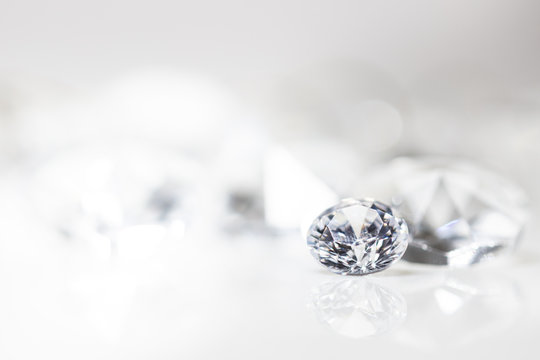 Diamant auf wei&szlig; mit Spiegelung vor wei&szlig;em Hintergrund, mehrere Diamanten in der Unsch&auml;rfe, Edelsteine mit Textfreiraum
