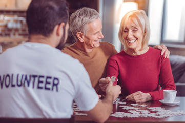So pleased. Positive delighted senior man turning head while embracing his wife