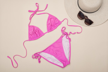 Pink swimsuit, hat and sunglasses. Beach wardrobe. Fashionable concept