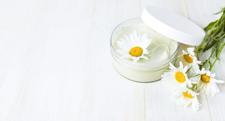 Fototapeta na wymiar Opened plastic container with cream and chamomile flower on a light background. Herbal dermatology cosmetic hygienic cream Spa concept organic cosmetic Natural beauty product.