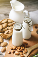 Almond and almond milk on a wooden table in the summer garden. Useful food.