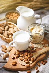 Almond and almond milk on a wooden table in the summer garden. Useful food.