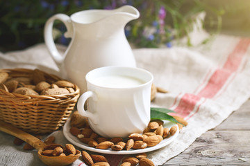 Almond and almond milk on a wooden table in the summer garden. Useful food.