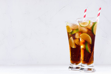 Cool cocktail rum and cola in elegant long glasses with bubbles and ice cubes in soft light white interior. Copy space.
