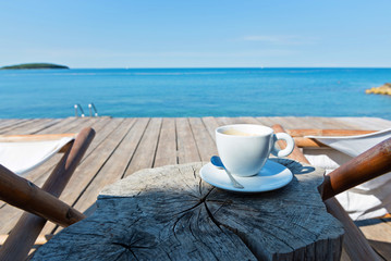 Wooden floor and sea view with chaise-longues and coffee - obrazy, fototapety, plakaty
