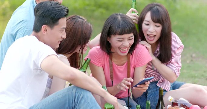 Young friends taking selfie on mobile phone in the park when going picnic