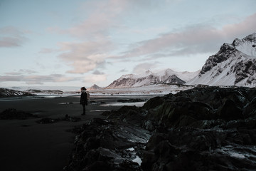 Person standing on a black sand beach in Stokksnes, Iceland