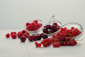 Fresh raspberries, red currants and cherries scattered on the table. soft focus
