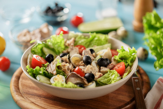 Tuna salad with lettuce, cherry tomatoes, quail eggs, olives and cucumber on the plate.