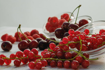 Mix of fresh raspberries, red currants and cherries scattered on the table. soft focus