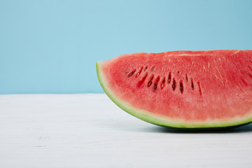 close up view of fresh watermelon slice on white surface on blue background