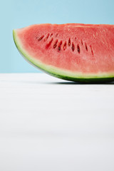 close up view of fresh watermelon slice on white surface on blue background
