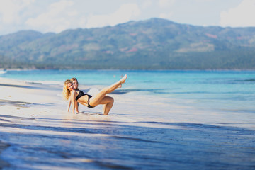 Two girls do exercises on the beach