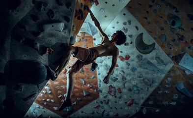 Free climber young man climbing artificial boulder indoors © master1305