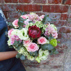 Bouquet with exotic flowers and plants against the backdrop of a brick wall. Beautiful, author's bouquet of florist. Work in a flower shop