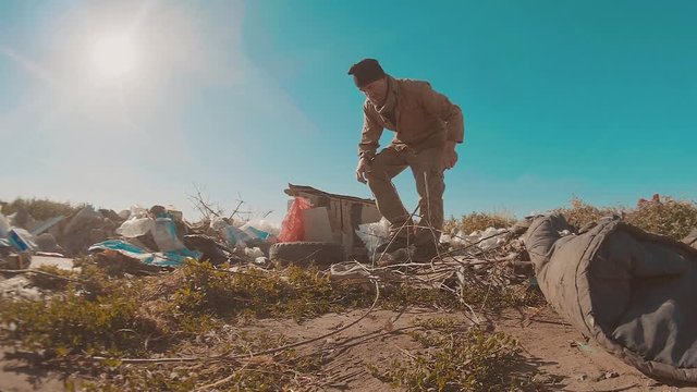 dirty homeless man at the lifestyle dump slow motion video. homeless roofless person looking for food in a dump. refugee homeless illegal immigration poverty concept