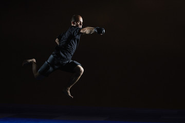 Obraz na płótnie Canvas Athlete in black gloves beats with a hand in a jump