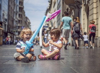 Boy and girl sitting on the pedestrian street in the city, smiling and having fun