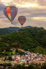 hdr shot of colorful hotair balloon flying over city in the mountain during sunset giving colorful sky color (selective focus and tone adjustment in post process)