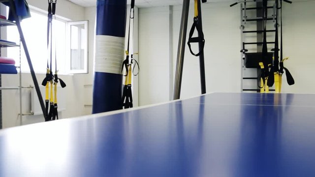 Piece of sports space, gym interior with ping pong table, home gym, machine, moving punching bag,