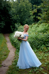 Fototapeta na wymiar Bride in nature, with a large bouquet of peonies. In a blue, embroidered dress. Wedding walk, photo shoot