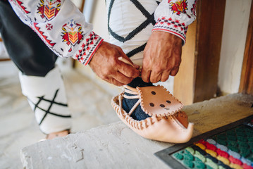Man putting on  traditional bulgarian leather shoes - Tsarvuli  - obrazy, fototapety, plakaty