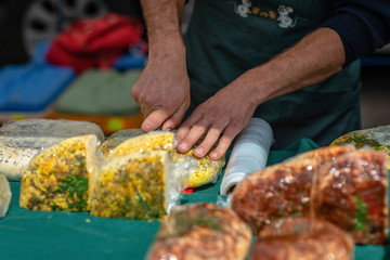 The man with the knife cuts the cheese market on the table.