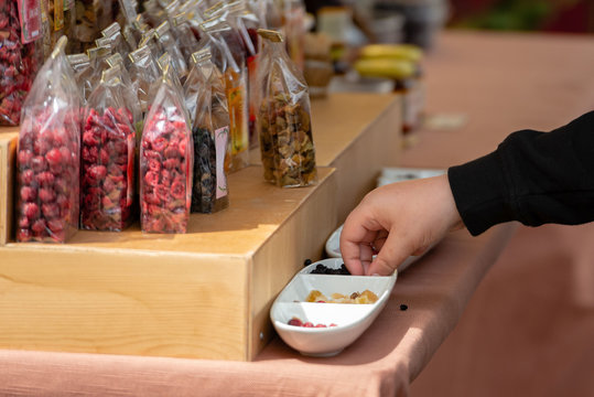The buyer will take candy from the bowl of sweets tasting samples.