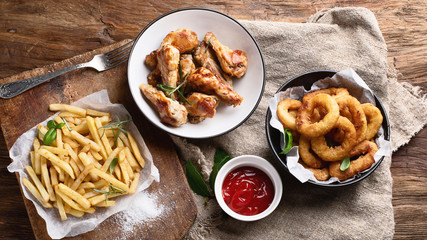 Fast food snacks - onion rings, fries and chicken wings