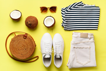 Female white sneakers, jeans, striped t-shirt, rattan bag, coconut and sunglasses on yellow...