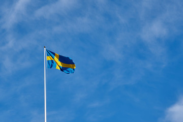 Flag of Sweden against a blue cloudy sky on a background. Copy space for text.