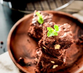 luxurious dessert, chocolate brownie cake in a wooden plate on a black background, space for text