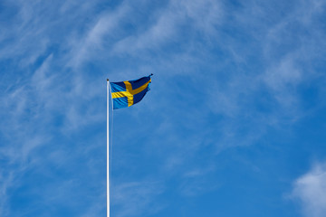 Flag of Sweden against a blue cloudy sky on a background. Copy space for text.