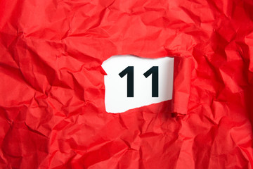 rotes zerknülltes Papier, aufgerollt mit Zahl elf - 11 auf weißem Untergrund