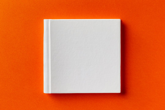 Mockup Of Square White Closed Book With Leather Cover Isolated At Orange Design Paper Background.