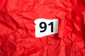 rotes zerknülltes Papier, aufgerollt mit Zahl einundneunzig - 91 auf weißem Untergrund