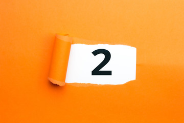Zahl zwei - 2 verdeckt unter aufgerissenem orangen Papier
