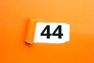 Zahl vierundvierzig - 44 verdeckt unter aufgerissenem orangen Papier