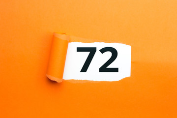 Zahl zweiundsiebzig - 72 verdeckt unter aufgerissenem orangen Papier