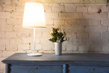 Lamp and bouquet with flowers on an old chest of drawers