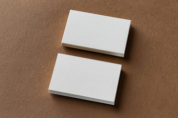 Mockup of two white business cards stacks at craft textured paper background.