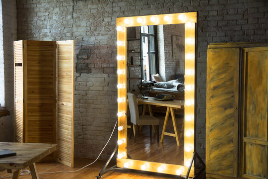 Large full-length mirror in a room with a brick wall and a window