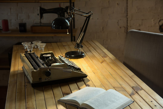 An old typewriter illuminated by a lamp on a wooden lacquered table