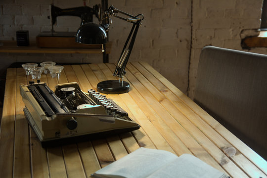 Typewriter illuminated by a table lamp on a wooden table