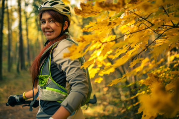 Fototapeta na wymiar Photo of girl in helmet on bicycle in autumn forest